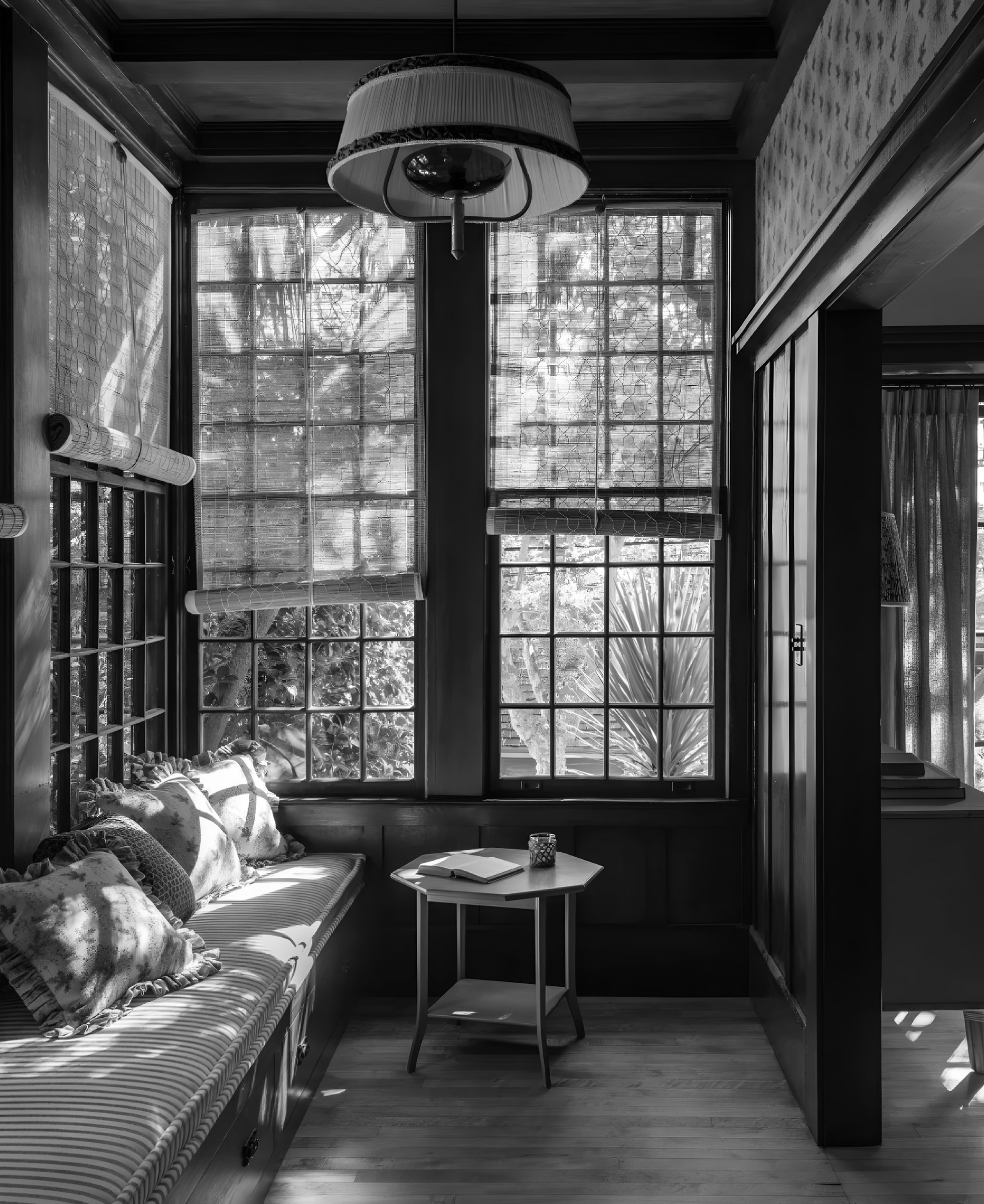 A window seat in a panelled room, a book open on a small table